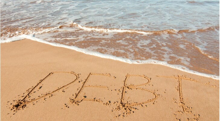 "DEBT" written on a beach