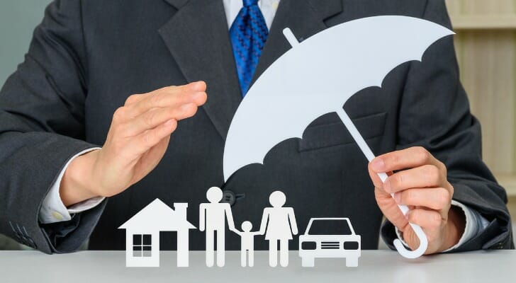 Insurance broker holding a picture of an umbrella over a picture of a family.