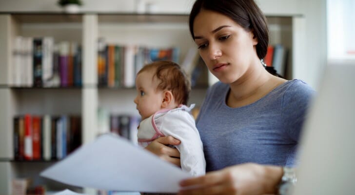 Mother holds baby while checking a tax document