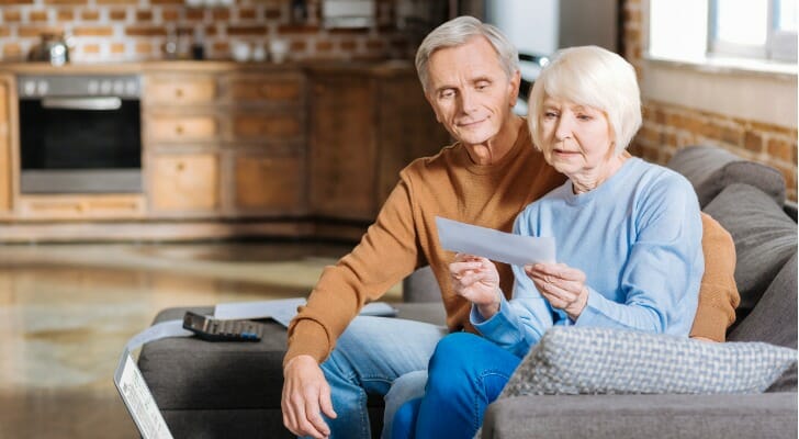 A retired couple looks at a Social Security check together. A retirement strategy known as the Social Security bridge is one way to create an enlarged stream of guaranteed income without an annuity. 