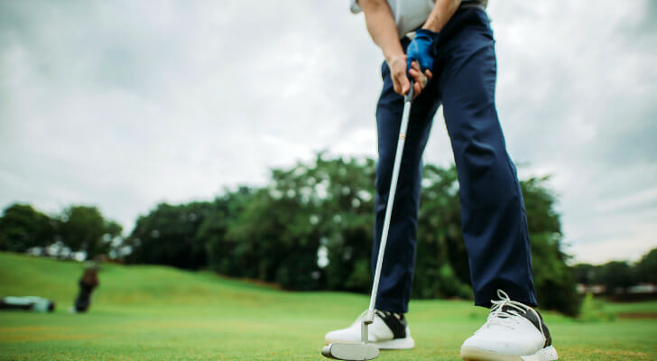 Image shows a golfer standing on a golf course, holding a club and getting ready to swing. SmartAsset analyzed various datasets to identify the best cities for golfers.