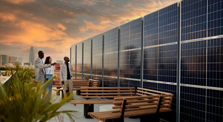 图片显示几个人在检查一系列的太阳能电池板。COP26气候变化会议将绿色投资重新置于聚光灯下。