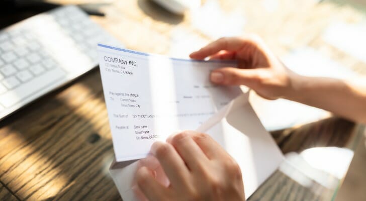 Image shows a person's hands holding a paycheck taken out of an envelope just received in the mail. SmartAsset used various data to conduct its latest study on the best places to live on a $60,000 salary.