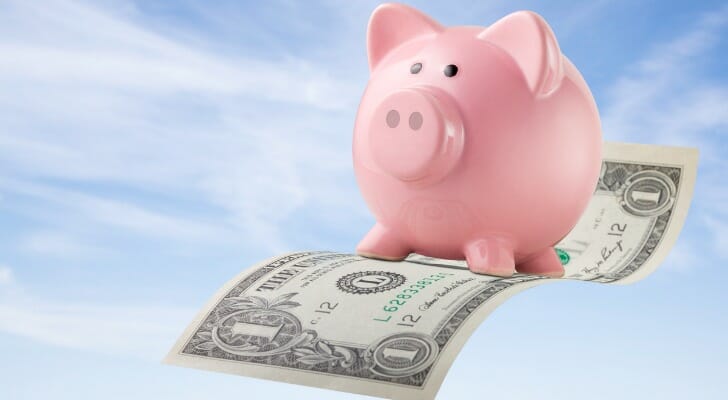Piggy bank floating on an airborne dollar bill