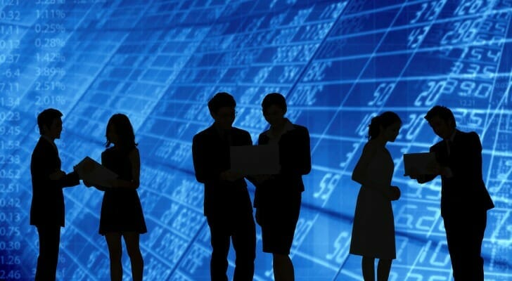 Stock brokers in front of a digital stock price screen