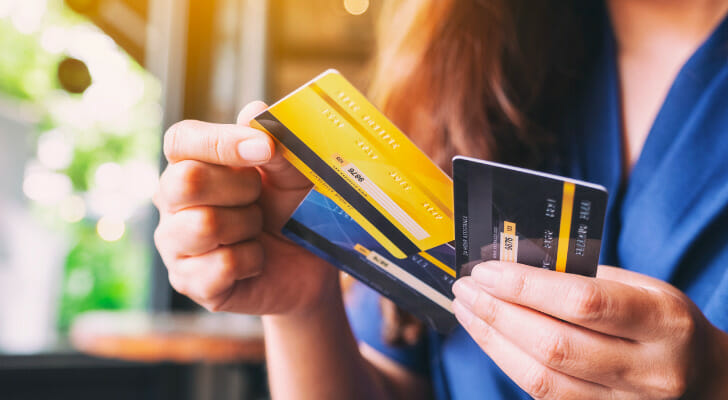 Image shows a person holding three credit cards and choosing one of them to make a purchase. SmartAsset analyzed data to conduct its latest study on the best places to get out of credit card debt.