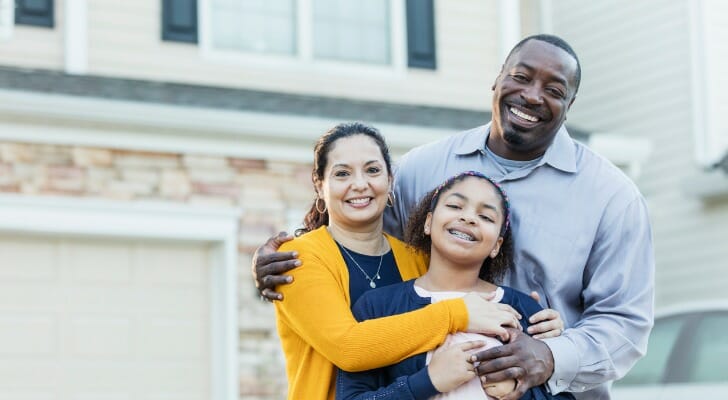 Image shows a mixed-race family of three standing and smiling in front of their new home. In this study, SmartAsset analyzed data across four categories - market favorability, affordability, livability and employment - to find the best cities for first-time homebuyers.
