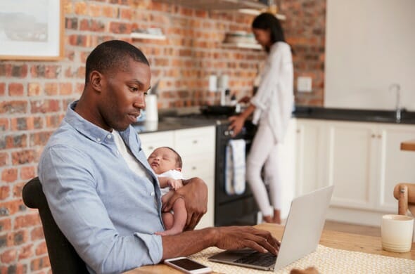 father-on-laptop-holds-newborn-son-as-mother-makes-meal-picture-id672419722.jpg