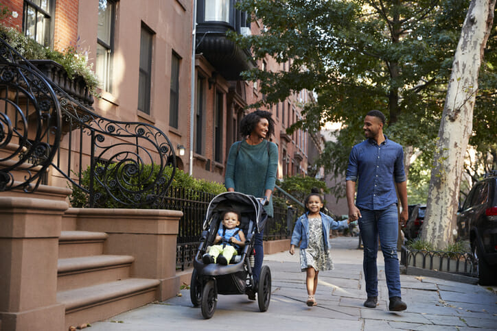 Image shows a Black American family walking down a tree-lined street. SmartAsset used data related to income, homeownership and more to determine the cities where Black Americans fared best economically leading up to 2020.