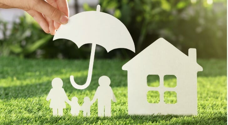 Paper umbrella over a paper house and family