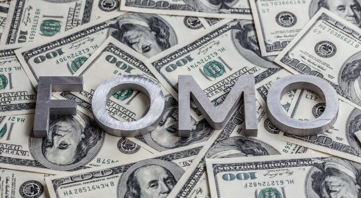 "FOMO" letters on top of many $100 bills