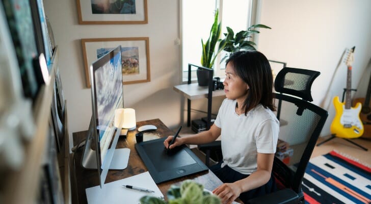 Image shows an Asian American person working from home. SmartAsset analyzed various data in order to conduct its study on where Asian Americans fare best economically.