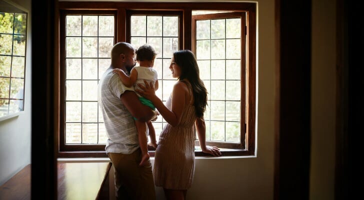 Image shows a small family - two parents and their child - standing in their home. SmartAsset analyzed data from various sources to conduct its latest study on the best cities for an affordable family home.
