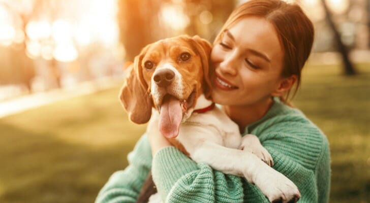 Image shows a pet parent playing with their dog. SmartAsset analyzed data from various sources to identify and rank the most dog-friendly cities in America.