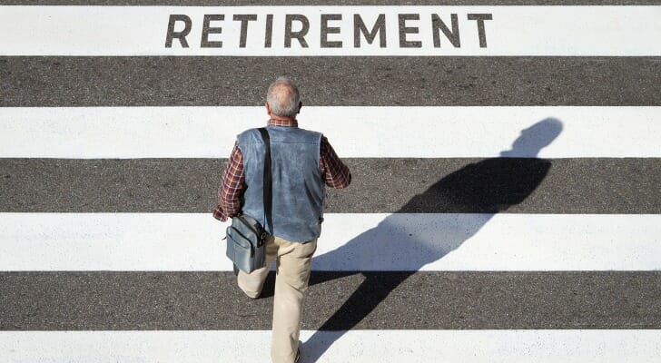 Man walking on a road with the word "RETIREMENT" painted in front of him
