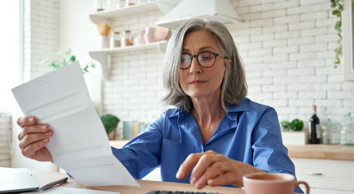 A retired woman calculates her expenses while sitting at her kitchen table. Researchers at Boston College recently explored the consumption rates of retirees and identified some significant long-term trends.