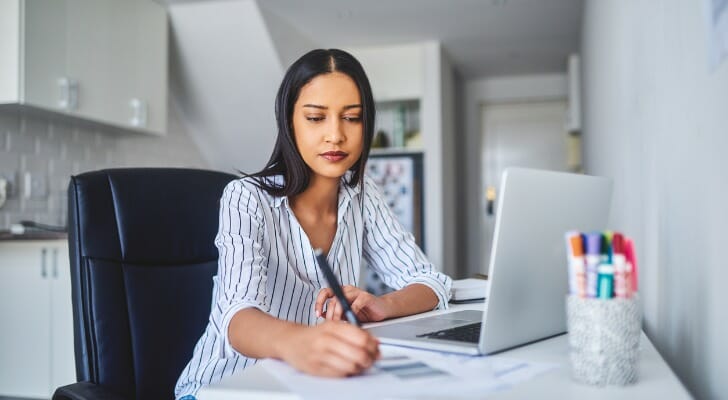 Image shows a young professional sitting in front of a laptop and taking notes for a work assignment. SmartAsset analyzed data from various sources to conduct this year's study on the best cities for young professionals.