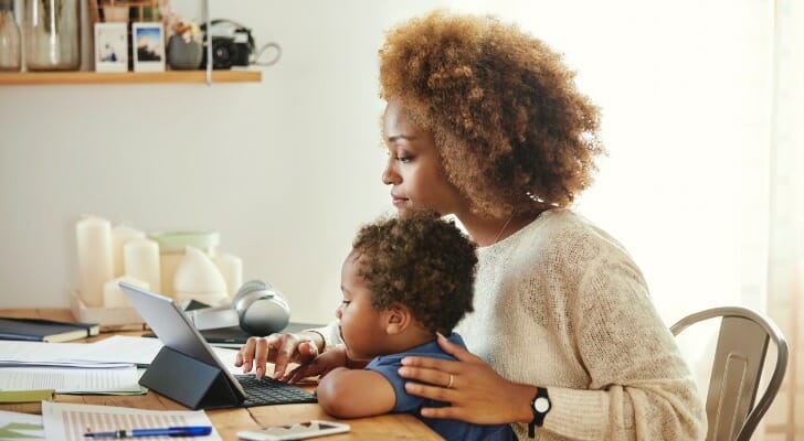 Image shows a parent working from home while taking care of their child as well. SmartAsset analyzed data on employment, housing costs, childcare costs, internet access and more to identify and rank the top cities for working parents.