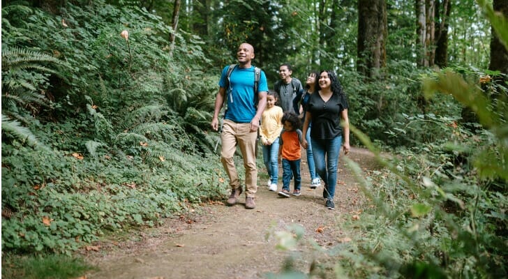 Image shows a family on a hike; they are walking on a dirt trail and are surrounded by trees. SmartAsset analyzed data from various sources to put together its study on the best places for outdoor enthusiasts to live and work.