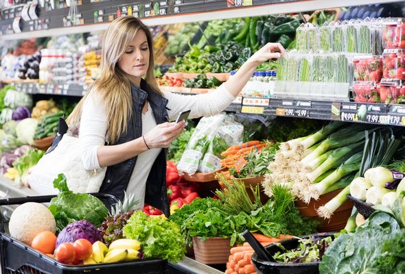 Woman grocery shopping while looking at her phone - Where Does Your Money Go?