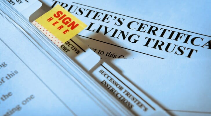 Image shows a pile of documents, the first of which is titled "Trustee's Certificate Living Trust." This kind of document would be necessary to open a trust bank account.