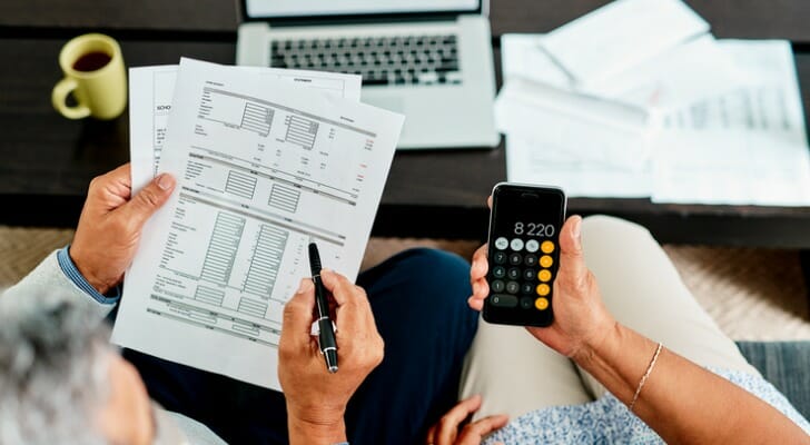 Image shows the hands of two people sitting next to each other; they are holding financial documents and a calculator while they complete some calculations about their employee stock ownership plan.