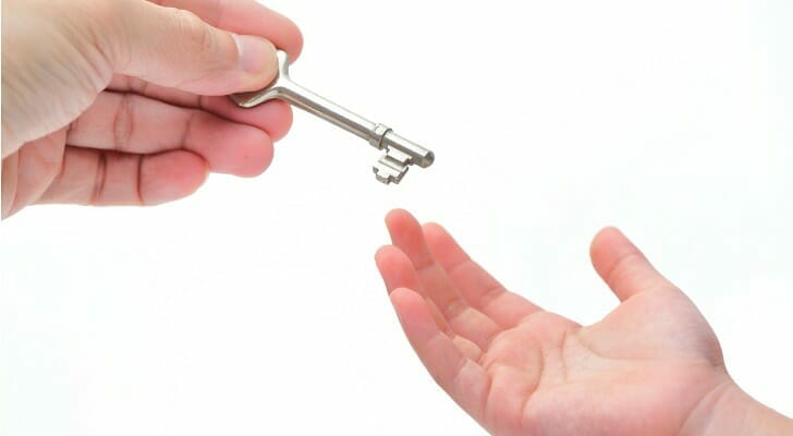Image shows one person's hand placing a key in another person's hand as a symbol of transfer of wealth.