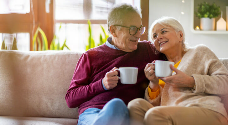图象显示了两个成年人，他是坐在沙发上和享受咖啡的老年人。伟德ios appSmartAsset分析了各种数据，以进行最新的研究，其中老年人最不经济地安全。