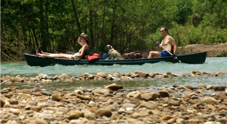 A couple with their dog in a canoe floating down an Arkansas river.