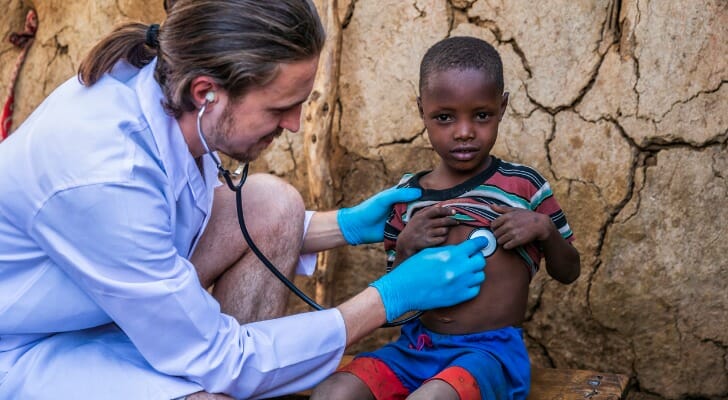 Medical worker checks the heartbeat of a small, impoverished child