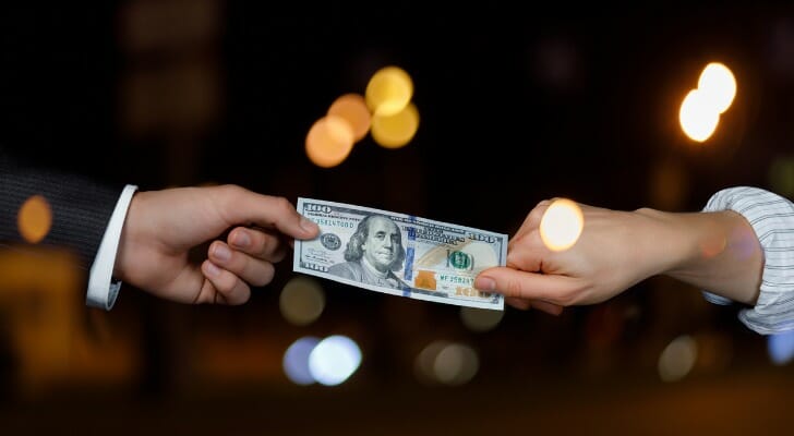 Two people tugging on a $100 bill