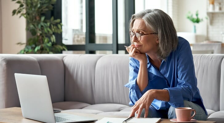 Image shows a retired individual looking at a laptop and paperwork to review their retirement benefits. SmartAsset conducted a study on the prevalence of employer-sponsored retirement plans in the U.S.